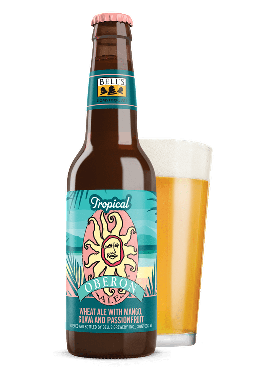 A bottle of a Tropical Oberon Ale sitting in front of a front glass