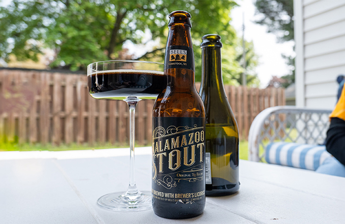 A bottle of Kalamazoo Stout, next to a Champagne bottle, next to a flute of Kalamazoo Velvet