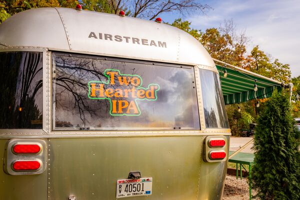 Airstream trailer with a two hearted ale neon sign displayed in the back window.